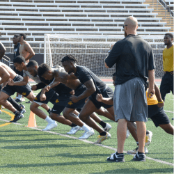 Strength coaches leading athletes through sprint training on the track