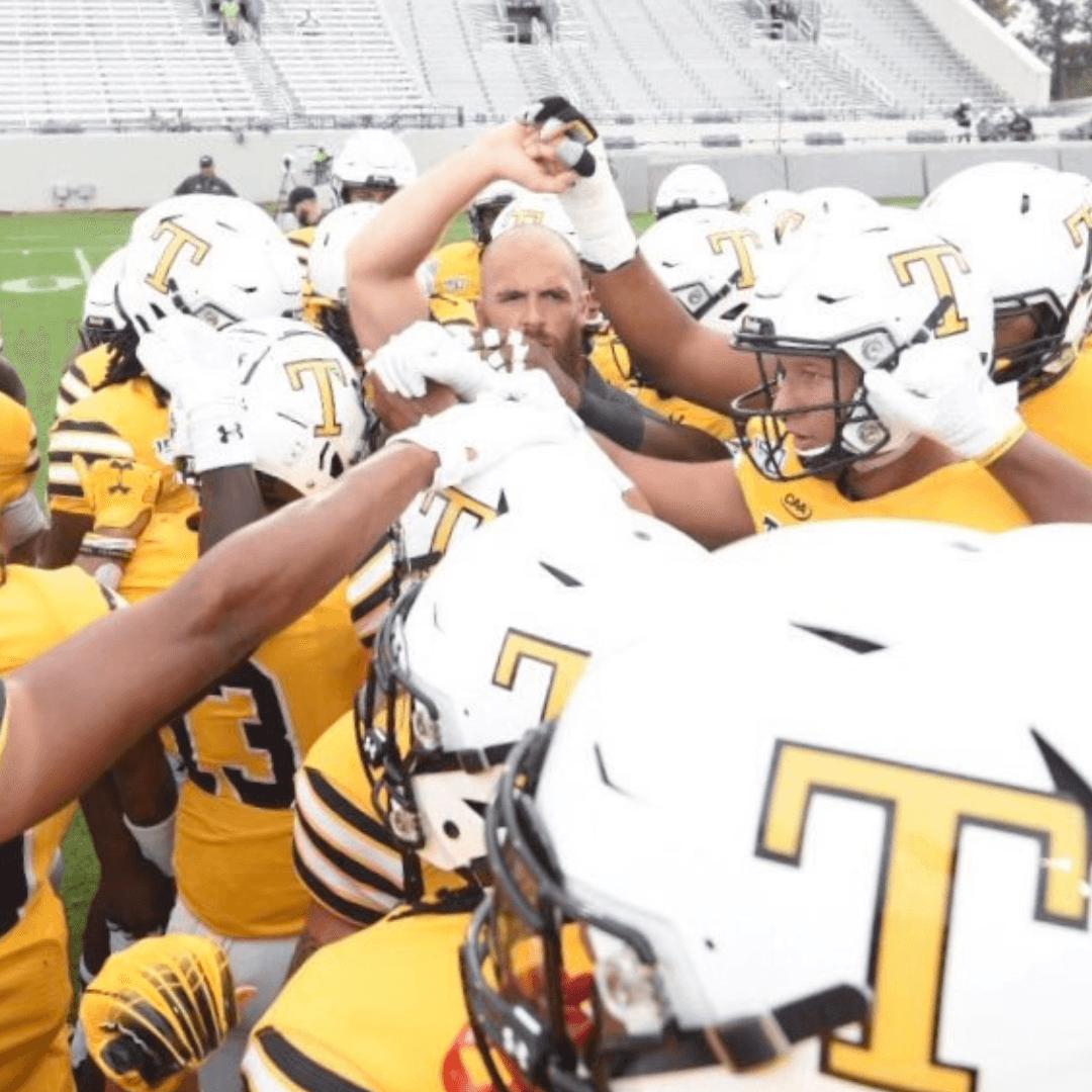 Football team huddle led by a strength coach