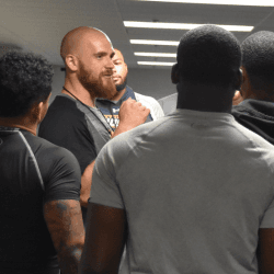 Director coaching athletes in the weight room